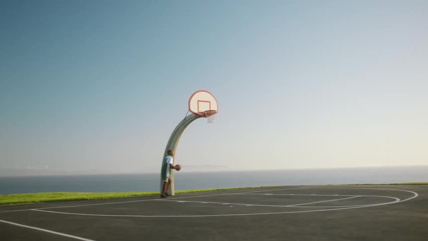 A man is playing basketball by himself in spring