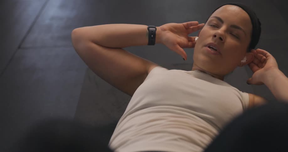 A woman breathes as she lays on her back and performs a core exercise