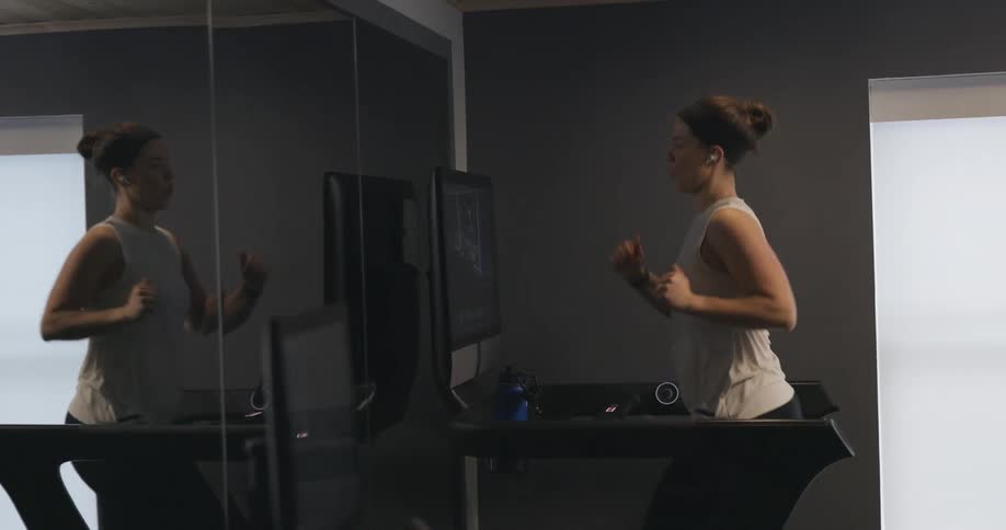 A woman is jogging on a machine in a gym