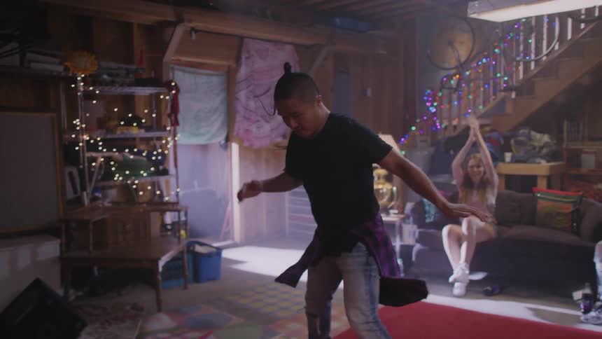 An Asian man dances and does flips in front of friends watching