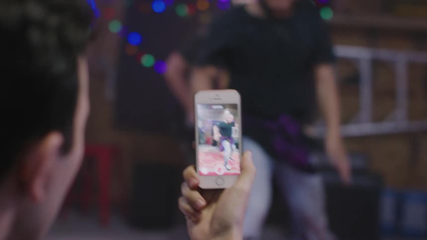 A man films a dancer and a musician from his smartphone