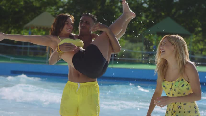 Three young friends playing and having fun in a water park on a sunny day