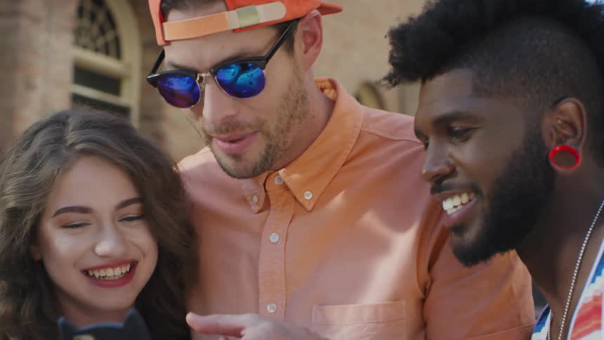 A group of friends react excitedly while watching a smartphone