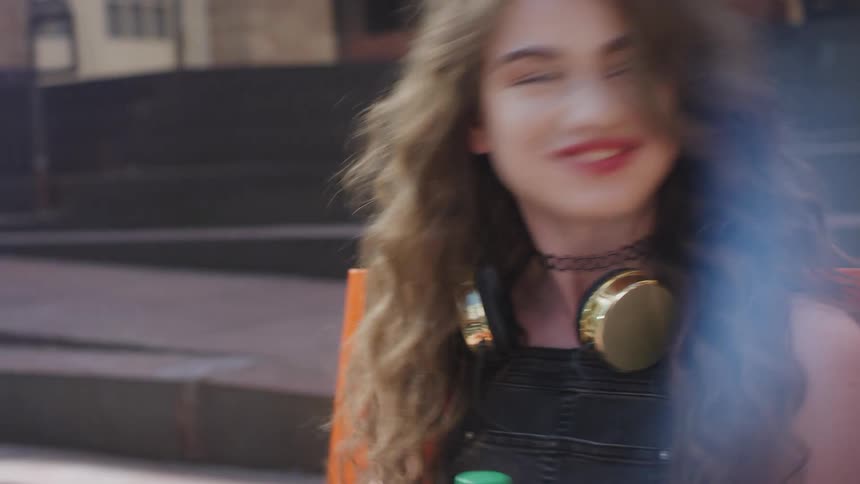 Teenager girl sitting on an orange bench outside with her friend talking and laughing