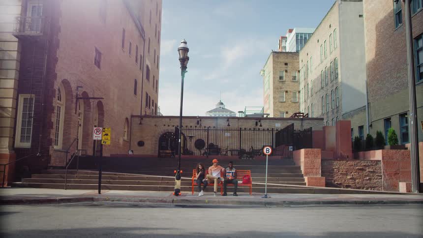 Three people are waiting for a bus in a city