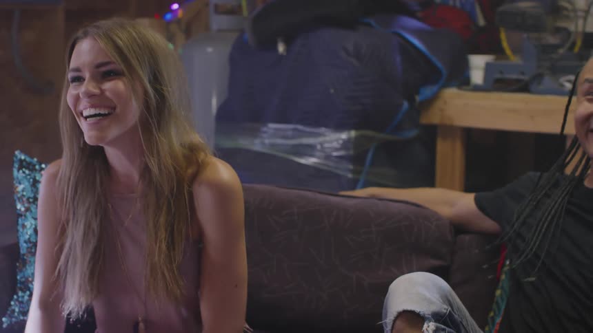 A group of friends laugh while sitting together on a sofa indoors