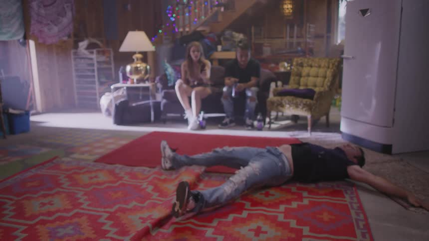 Man breakdancing inside the house while his friends are in the background watching and cheering