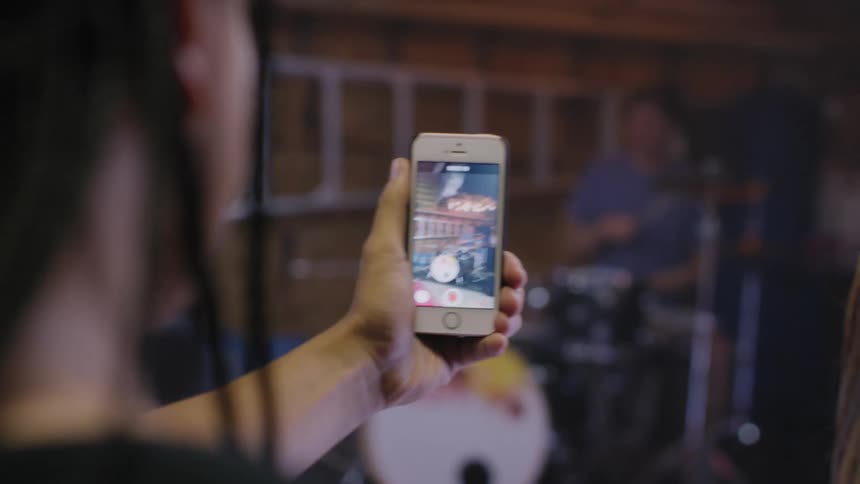 A man films a drummer from his smartphone
