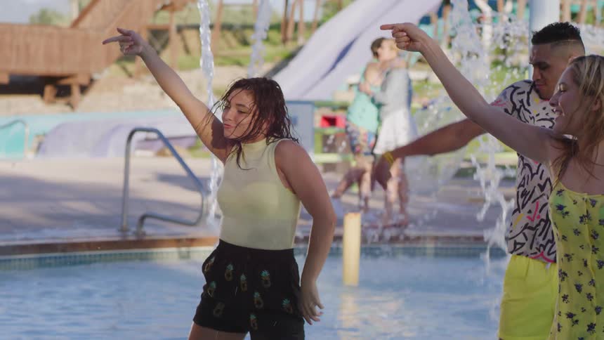 Three people dance in the water park