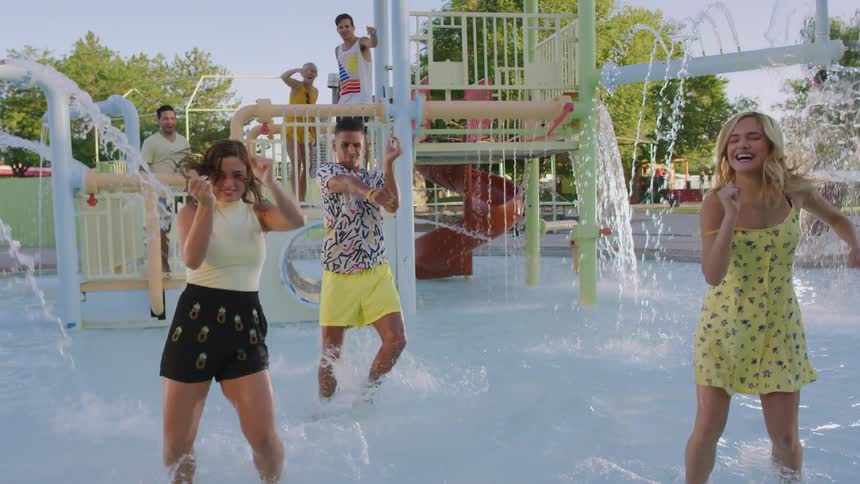 Young friends dance together in a shallow pool