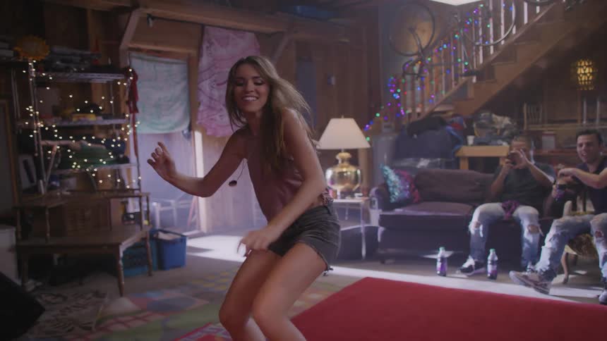 A young woman gets up and dances in front of her friends
