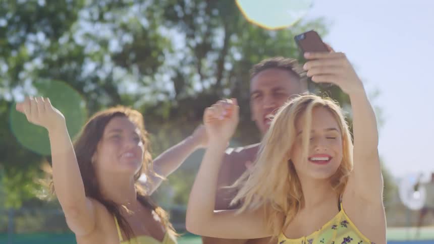 Three young friends take a selfie in the pool while dancing
