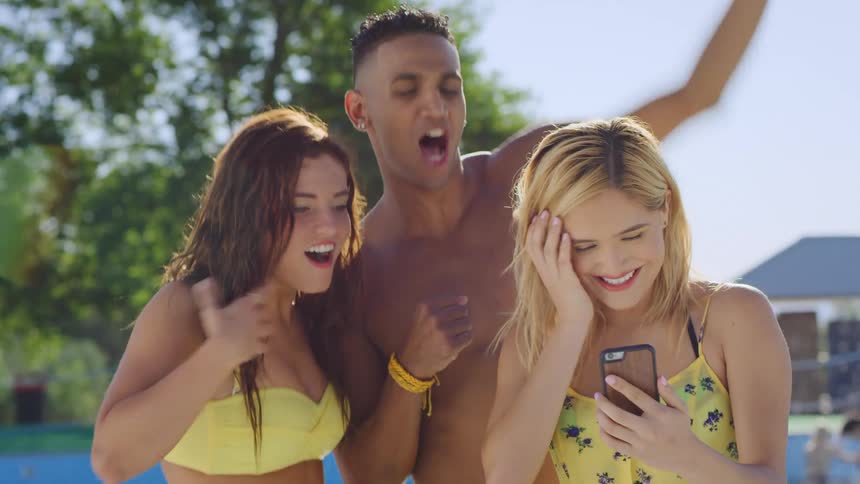 Teenagers in swimsuits watch a video on a smartphone