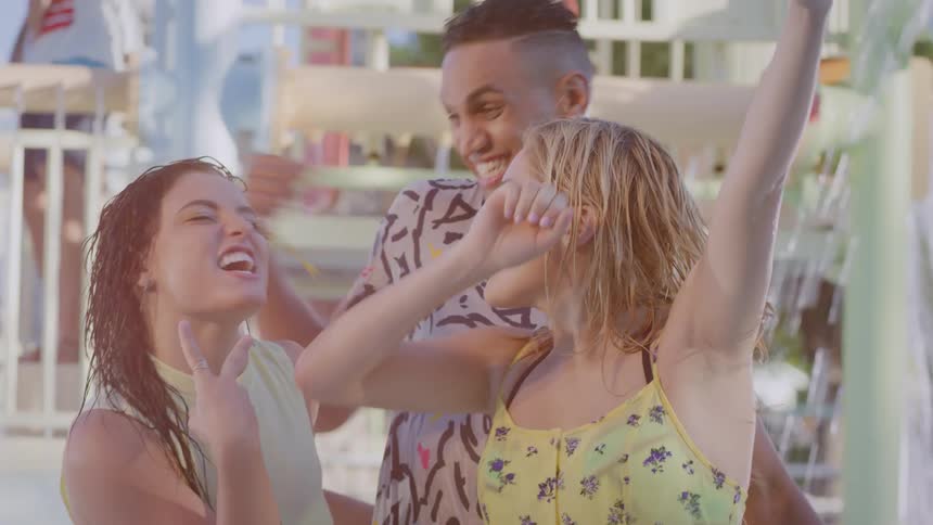 Three friends dance in a water park during a video call