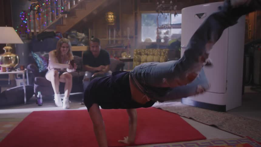 A man breakdances to live music in front of a group of friends