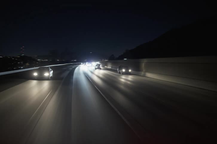 Vehicles move in traffic on the highway at night