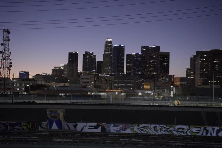 City skyscrapers seen from running train on tracks at dusk
