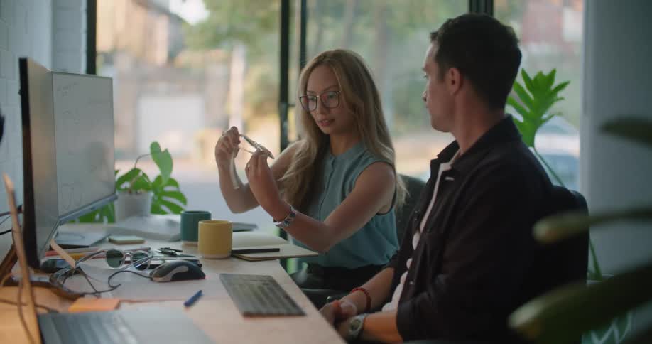 Man and woman sitting at the office desk looking to and analysing a sunglasses