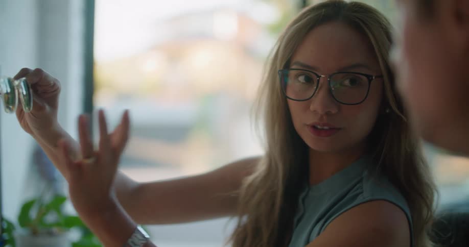A woman holds sunglasses up to a diagram on the screen