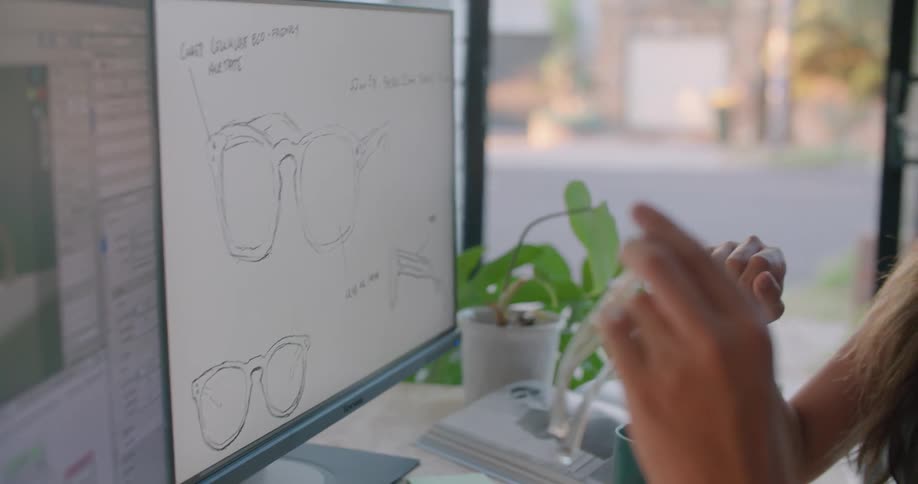 Two people look at designs of sunglasses in the office