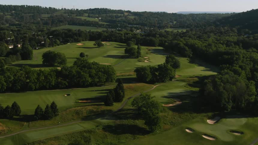 The green golf course has many trees around