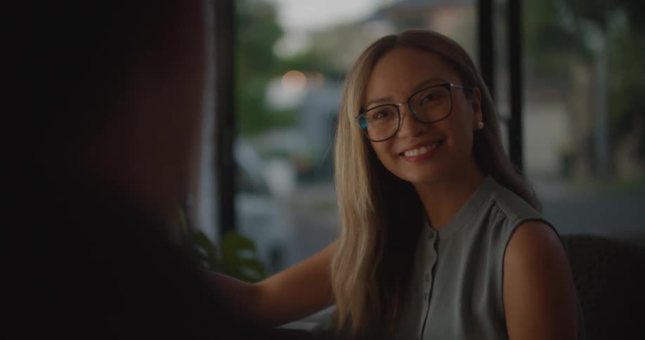 Woman sitting at the office desk holding a sunglasses and talking about the object with a man
