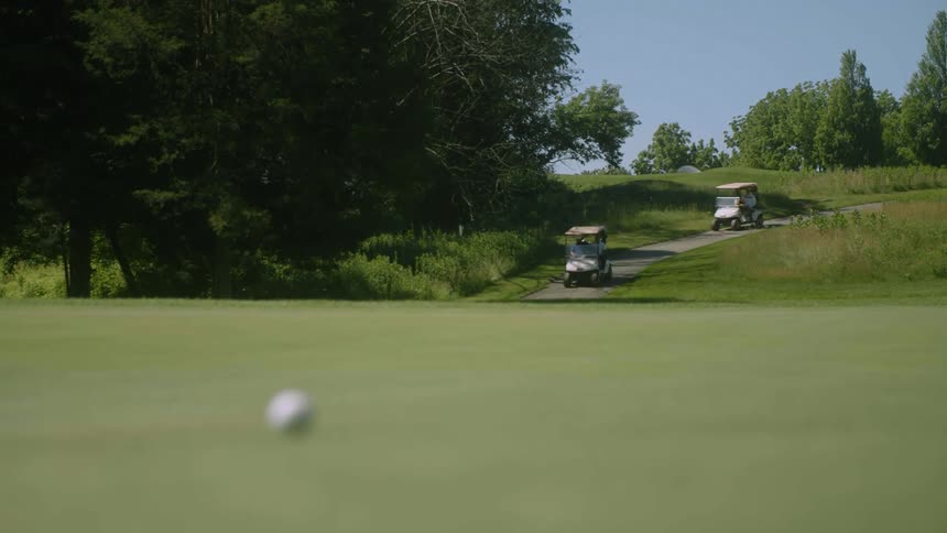 Golf cars driving into a golf field at a sunny day