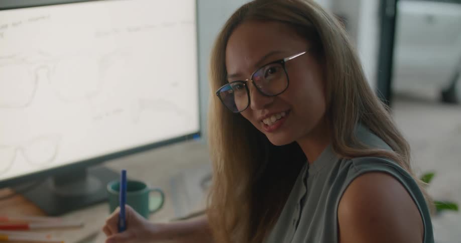 A woman talks to a coworker and holds a pen
