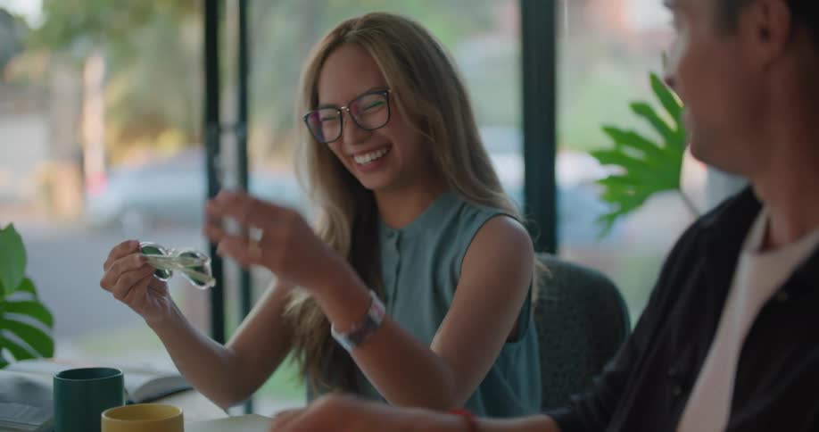 Two coworkers talk and look at sunglasses in the office