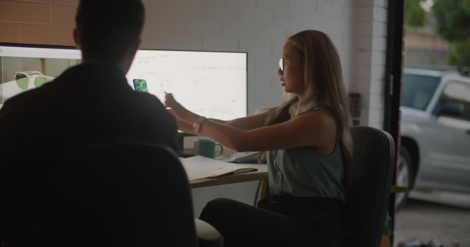 A woman slides over to the desk with her cell phone