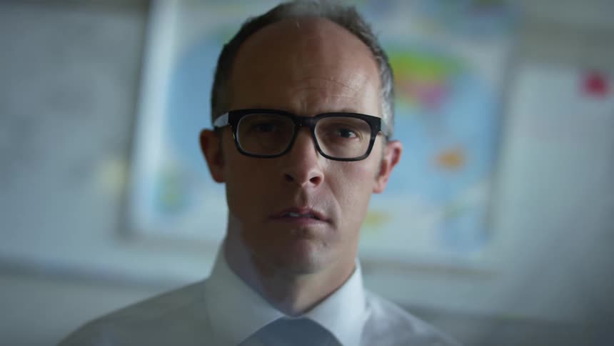 Man wearing glasses with eyes closed opens his eyes and stares