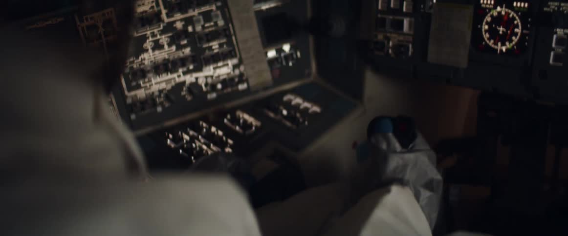 An astronaut in a cockpit holds a control