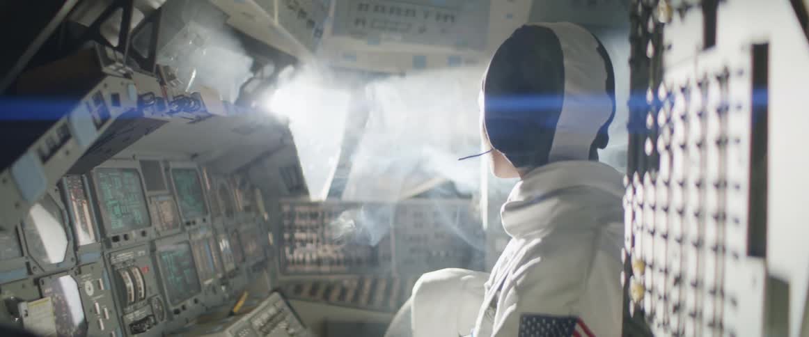 A woman wearing a uniform with an american flag sits in the cockpit of an aircraft