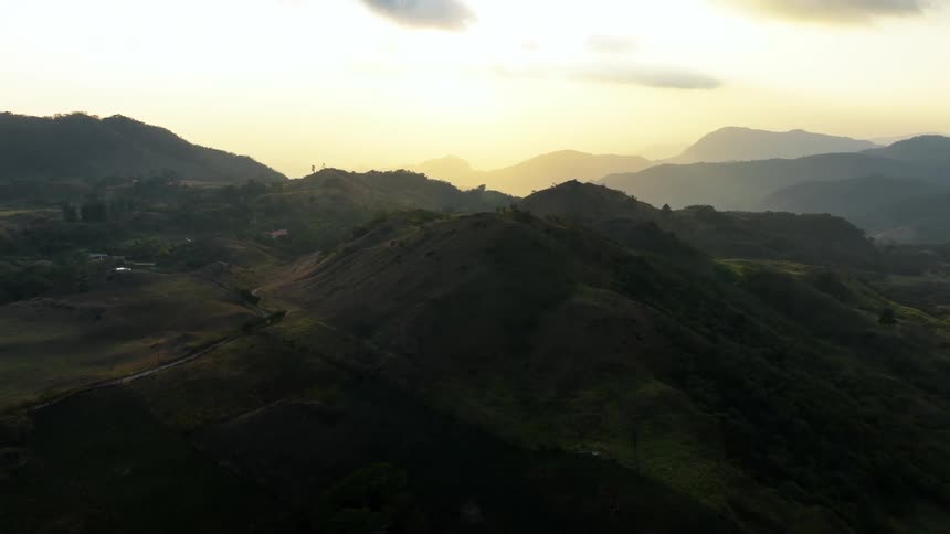 Trees and grass along a mountain ridge and silhouettes of mountains on the horizon