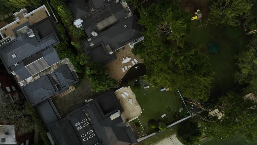 The camera spirals upwards away from the backyard of a residential home
