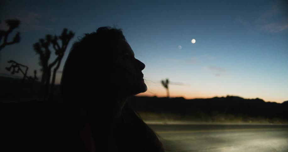 A woman stands by the side of the road