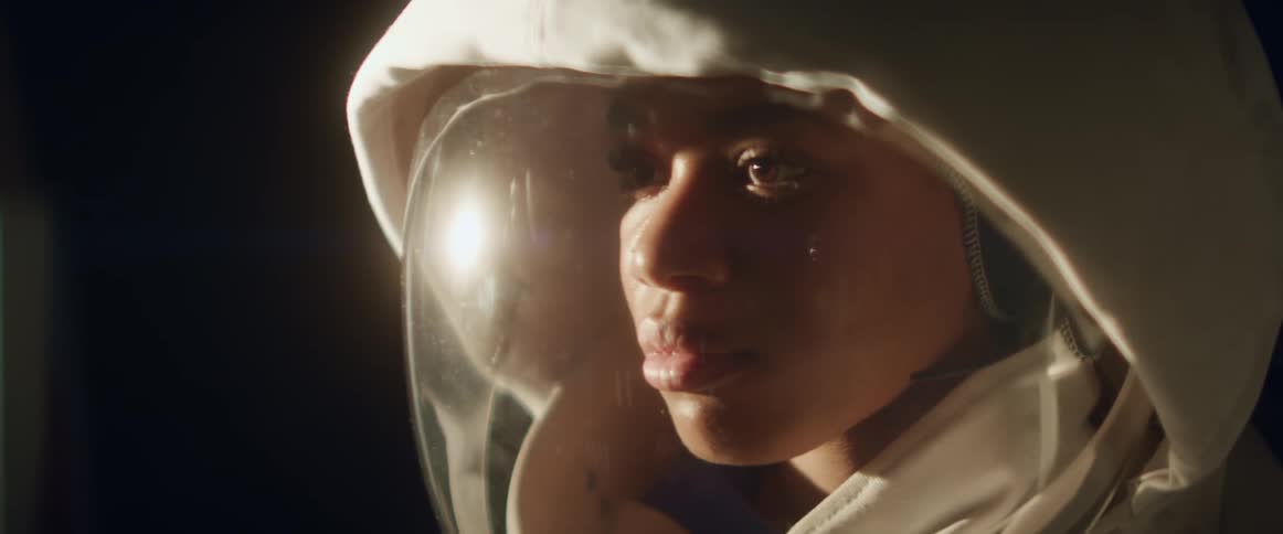 A young woman with an astronaut suit on looks around