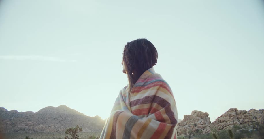 Latin woman standing outdoors wrapped in a colorful blanket