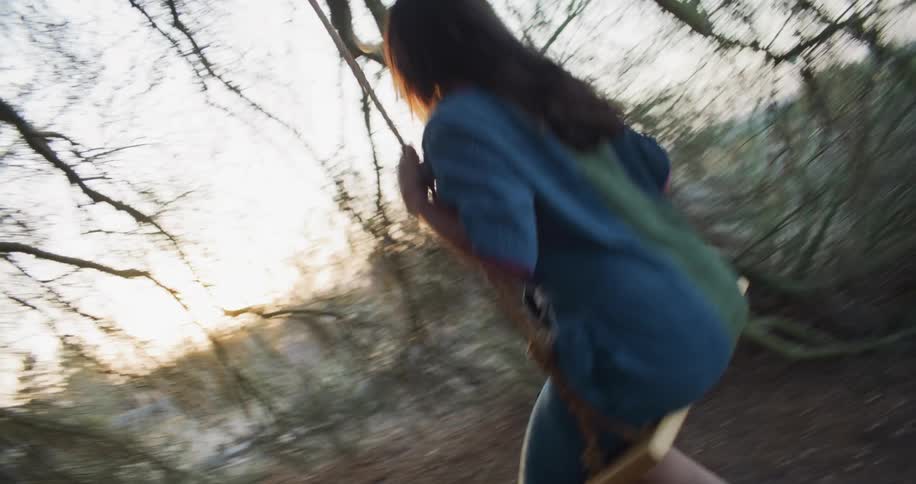 Latin woman having fun in a tree swing outdoors during sunset