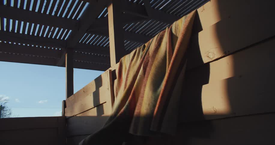 A blanket hanging on a porch blows in the breeze