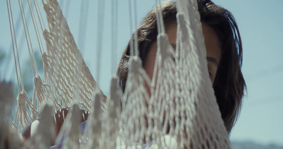 Woman swings in hammock chair under clear sky on sunny day