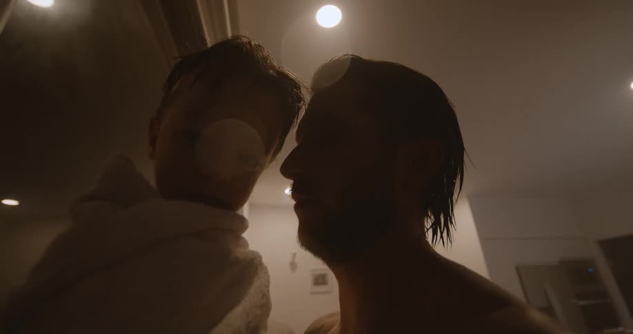 A man holds his son after a bath and gives him a kiss on the cheek