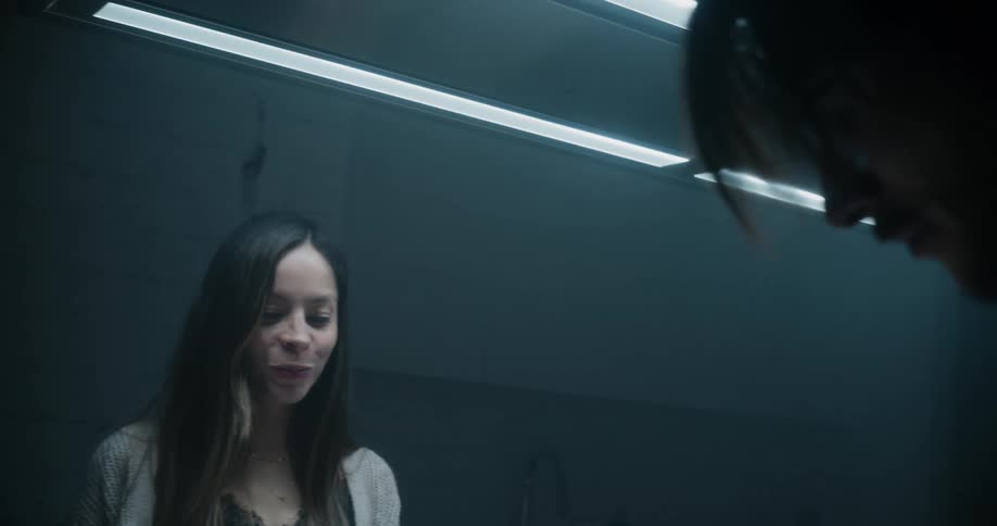 A man feeds food to his girlfriend in a dark room