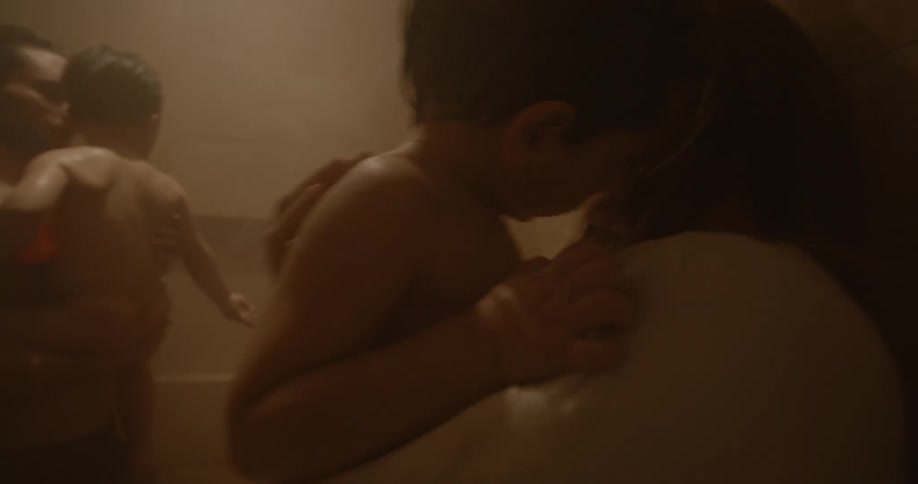 Mother and father holding their young boys and taking them to the shower while they look afraid