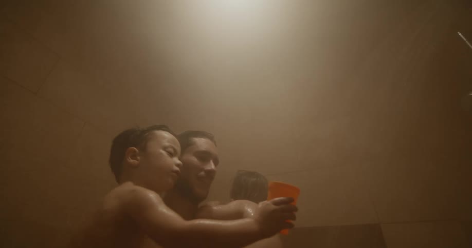 Father holding his two boys in the shower