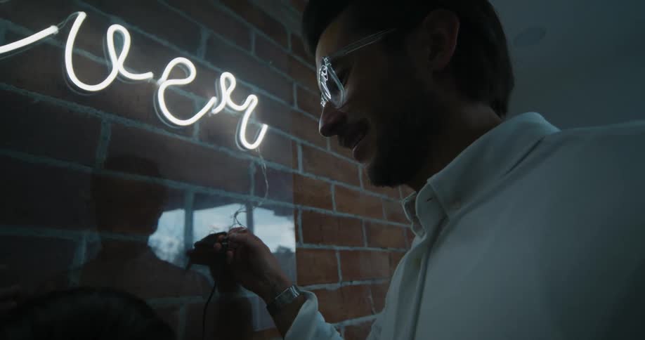 Father turning on the neon lights inside the house while his son stands next to him
