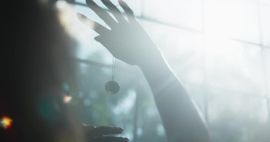 A woman lifts a necklace up to the barred window