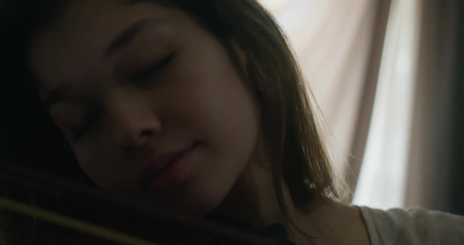 Woman playing violin with closed eyes indoors