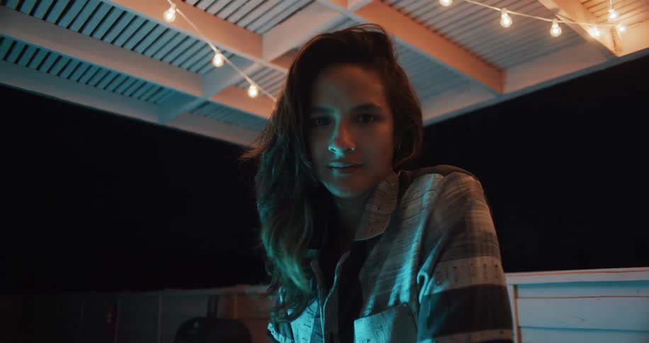 Woman wearing a shirt at the balcony of a house during the night