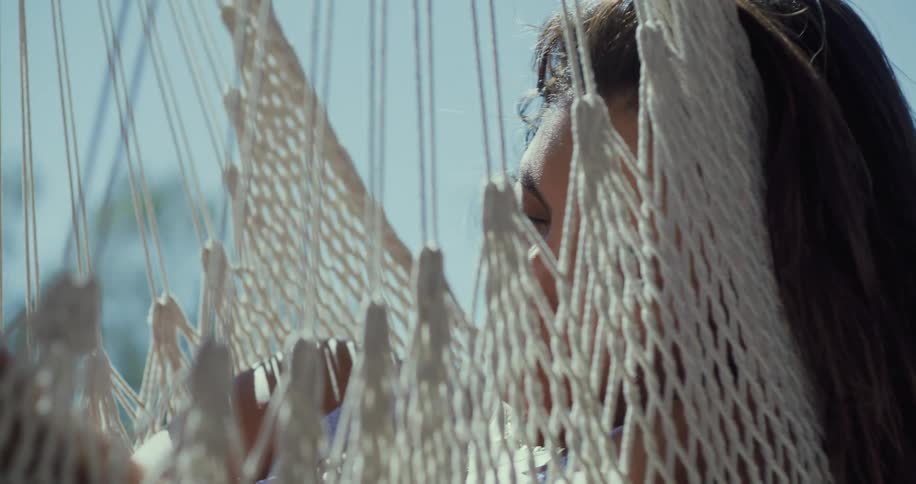 Latin woman sleeping and then waking up in the hammock outdoors at a sunny day